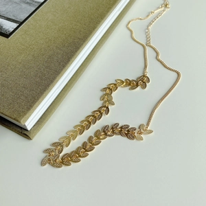 Macro view of gold leaf pattern choker necklace with adjustable chain on a book