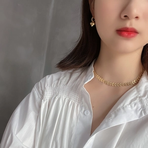 Close-up of gold leaf-shaped choker necklace and heart pendant earrings on a model