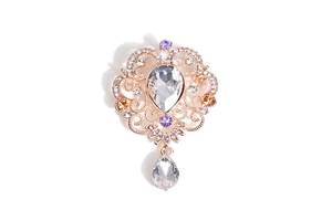 Macro view of gold baroque brooch with teardrop crystal pendant and filigree detailing