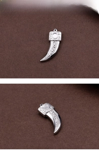 Detailed close-up of stainless steel wolf tooth pendant with ornate engraved patterns