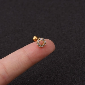 Macro shot of a small gold geometric zircon stud earring on a finger for size reference