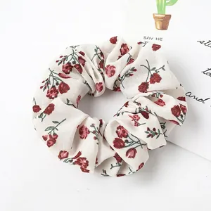 Detailed close-up of a floral scrunchie with vintage red roses on a beige fabric