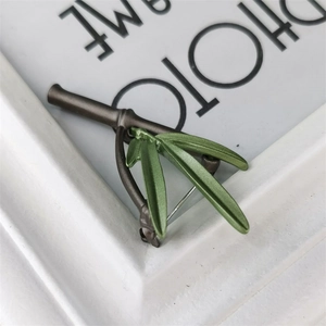 Detailed close-up of a bamboo-shaped brooch featuring green leaves and bronze stems