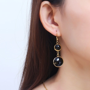 Elegant gold-framed black gemstone double drop earrings displayed on a model