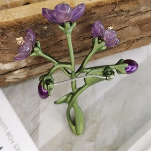 Detailed back view of a violet flower brooch showing the green pin and safety clasp