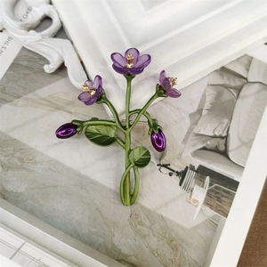 Detailed close-up of violet flower brooch with green metal leaves and freshwater pearl accents