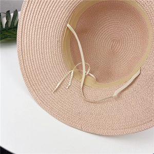 Pink woven straw sun hat with interior sweatband and chin strap on white background