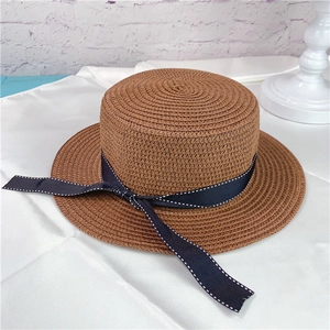 Brown woven straw boater hat with navy ribbon and white stitching detail for beach trips