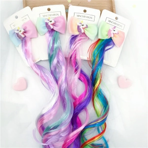 Close-up of four unicorn bow hair clips with long colorful spiral wig extensions