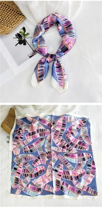 Detail view of square silk scarf with blue feather print and smooth satin texture