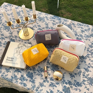 Dettaglio di quattro trousse trapuntate a fiori con toppa a agnello e chiusura a zip