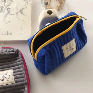 Dettaglio di pochette per trucchi in velluto a coste con ricami e cerniere colorate