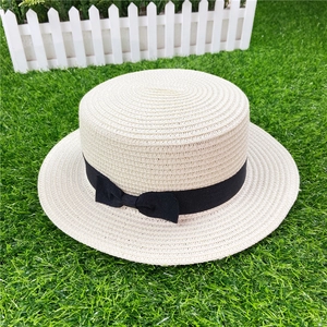 Top view of beige straw boater hat featuring a black ribbon band and elegant bow detail