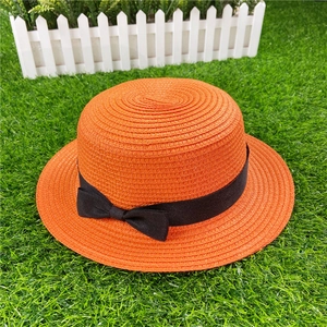 Detail of a bright orange straw boater hat featuring a stylish black ribbon bow decoration