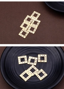 Macro detail of square gold titanium steel pendants with Roman numeral cut-out designs