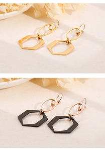 Détail montrant des boucles d'oreilles hexagonales dorées et noires au design minimaliste
