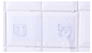 Waterproof adhesive hook on white tile showing strong adhesion under running water