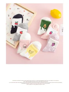 Detail view of colorful cotton socks featuring embroidered fruit patterns on pink background