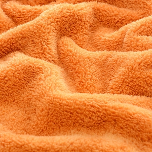 Close-up of soft orange coral fleece fabric with absorbent plush texture for cleaning