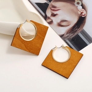 Detail of geometric wood and metal square earrings with circular alloy inlay