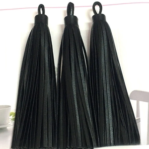 Close-up of three black PU leather tassel charms with metal rings for bags and keychains