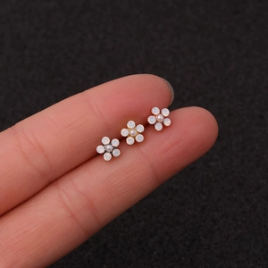 Close-up of three floral cartilage studs featuring opal petals and small pearl centers