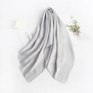 Detail showing the soft texture and smooth silk sheen of a light gray square neck scarf