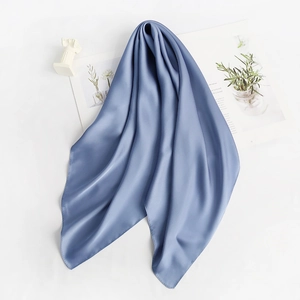 Blue silk scarf with smooth satin finish displayed on white background with decorative props