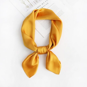 Detail of yellow silk satin neck scarf tied in a knot on a white minimalist background