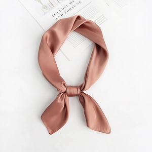 Close-up of pink square silk scarf tied in a bow knot on a minimalist background