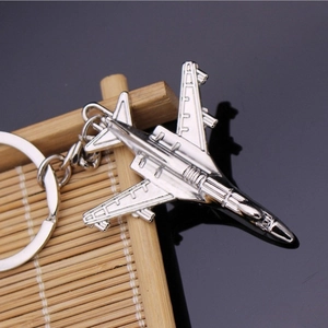 Close-up of a silver metal fighter jet keychain on a bamboo woven mat texture