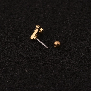 Macro shot of gold stainless steel screw-back stud earring on textured background