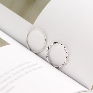 Detail of S925 sterling silver twist ring set showing minimalist Mobius textures on white book