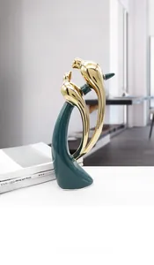 Detailed close-up of emerald green and gold ceramic lovebirds on an artistic pedestal