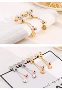 Detail of bow earrings with pavé gems, snowflake and bell charms in gold and silver