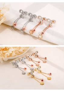 Detailed view of bowknot tassel earrings with snowflake charms in three metallic finishes