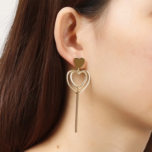 Boucles d'oreilles pendantes cœur en acier inoxydable doré portées par un mannequin