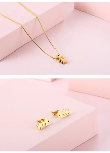 Detail von goldenem Fischgräten-Halsketten- und Ohrring-Set aus Edelstahl auf Rosa
