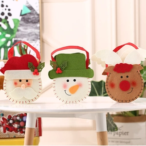 Three felt Christmas gift bags with Santa, snowman and elk designs on a white table