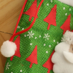 Detailansicht eines grünen Weihnachtsstrumpfes mit roten Baummustern und Nikolaus-Plüsch