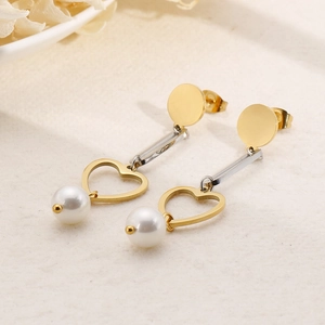 Elegant gold drop earrings with hollow heart charms and white pearls on a soft background