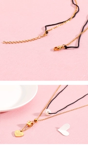 Detail of layered gold necklace showing lobster clasp and engraved heart pendant