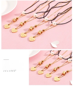 Detail of heart alphabet pendants with pearls on a dual gold and black layered chain