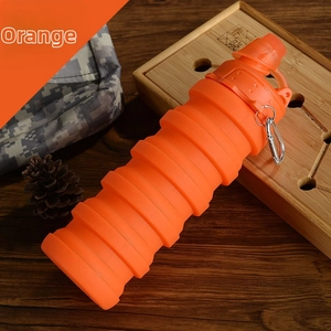 Orange collapsible silicone water bottle with carabiner hook on a wooden table setup