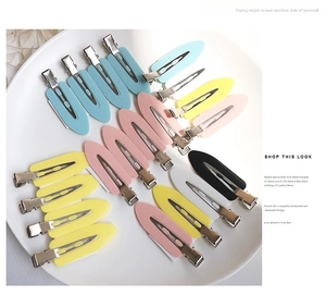 Detail shot of multi-colored seamless hair clips arranged neatly in a white ceramic dish