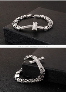 Macro detail of men's stainless steel Byzantine chain with cross pendant on black leather