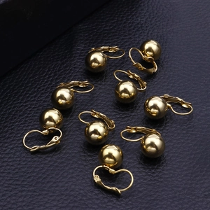 Polished golden spherical stud earrings displayed on a black leather background