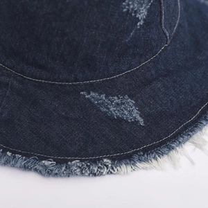 Macro shot of dark blue denim bucket hat showing vintage distressed frayed edge detail