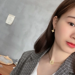Close-up of golden 925 silver flower necklace and heart earrings on a stylish model