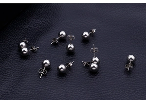 Macro shot of twelve silver stainless steel ball earrings on dark leather texture
